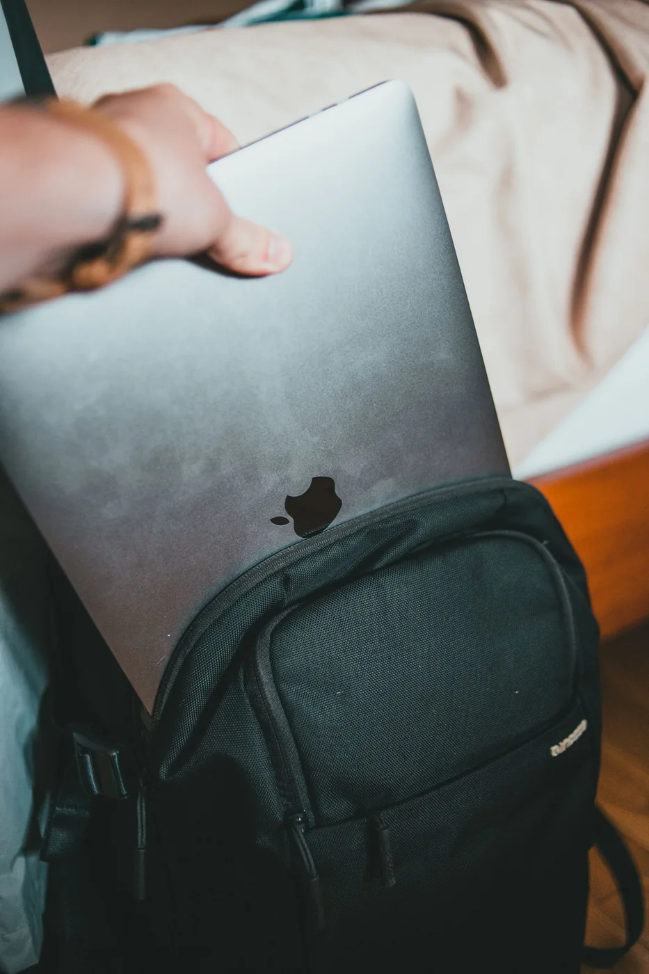 Person placing a laptop in a black backpack