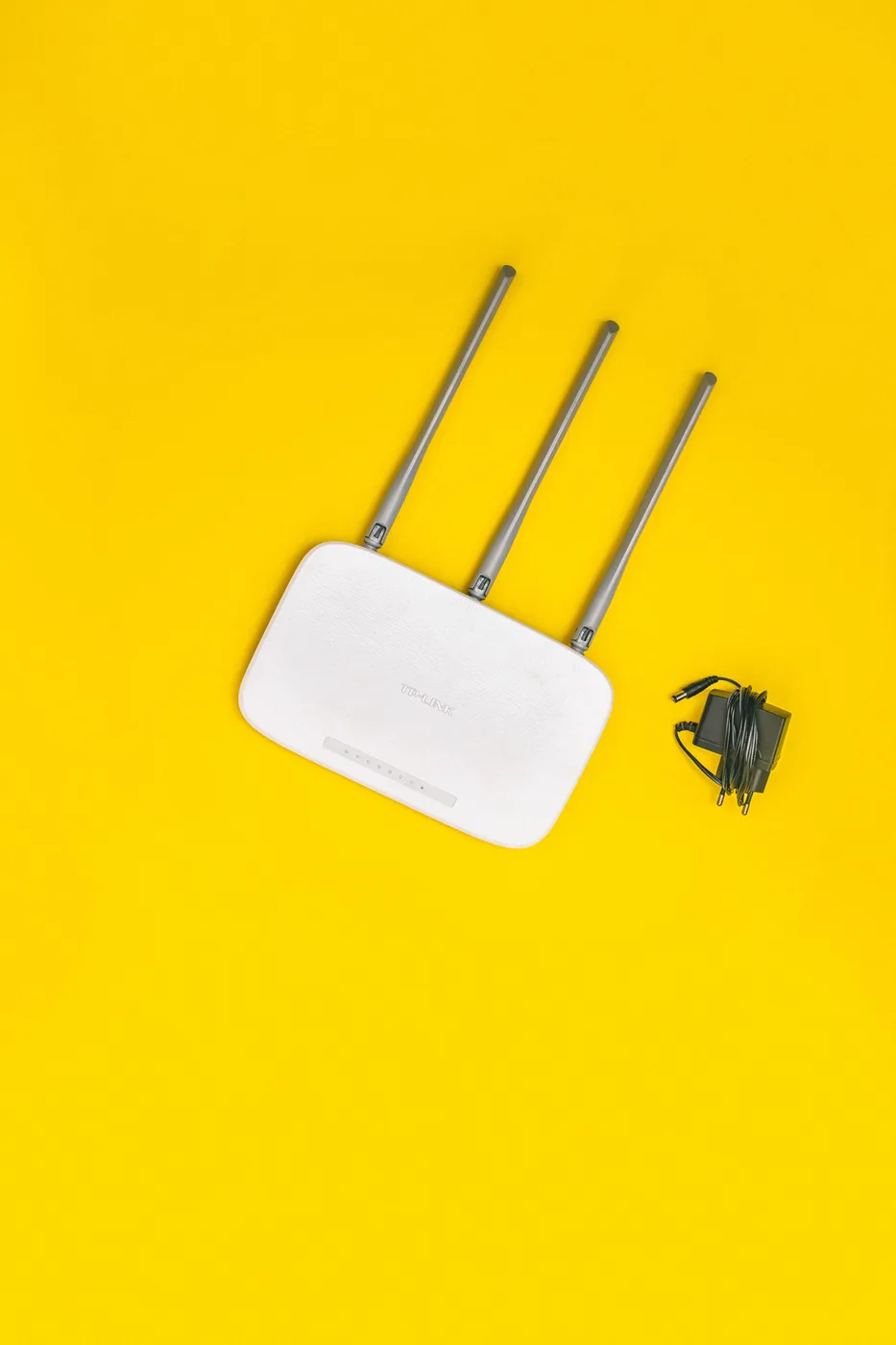 White wireless router and its cables arranged on a yellow surface