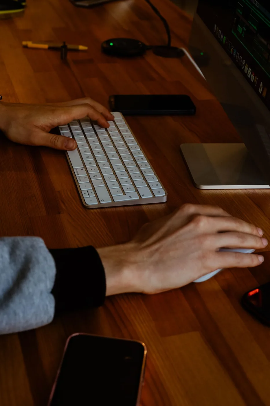 Hands using a computer keyboard and mouse at a working desk