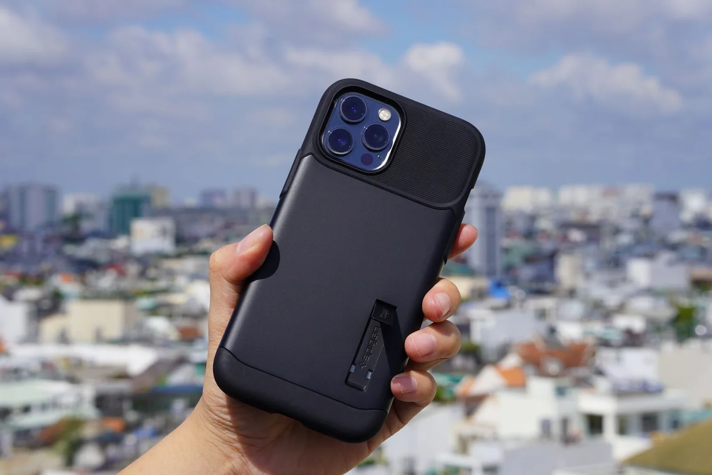 Hand holding a smartphone in a black case against a city skyline