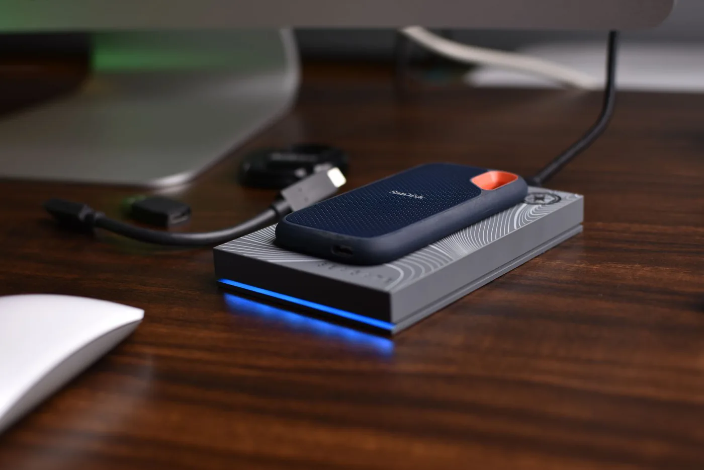 Portable solid state drive with connected cables on a wooden desk
