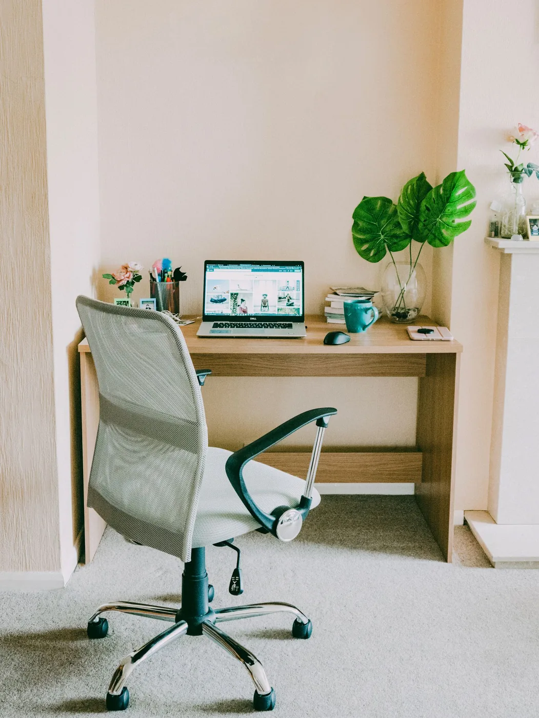 Laptop on a compact white desk beside a window and a green plant