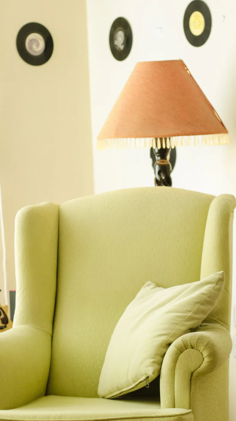 Green armchair and a lamp in a warmly lit living room corner