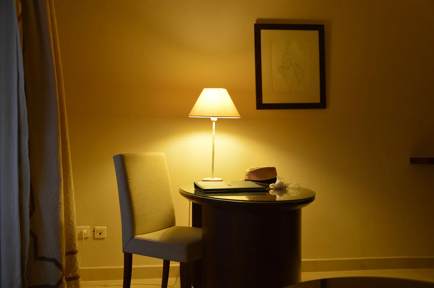 Glowing table lamp beside a chair in a warmly lit room