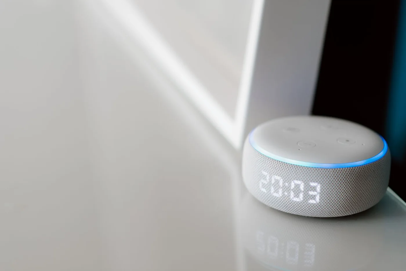 Fabric-covered smart speaker with a digital clock display on a table