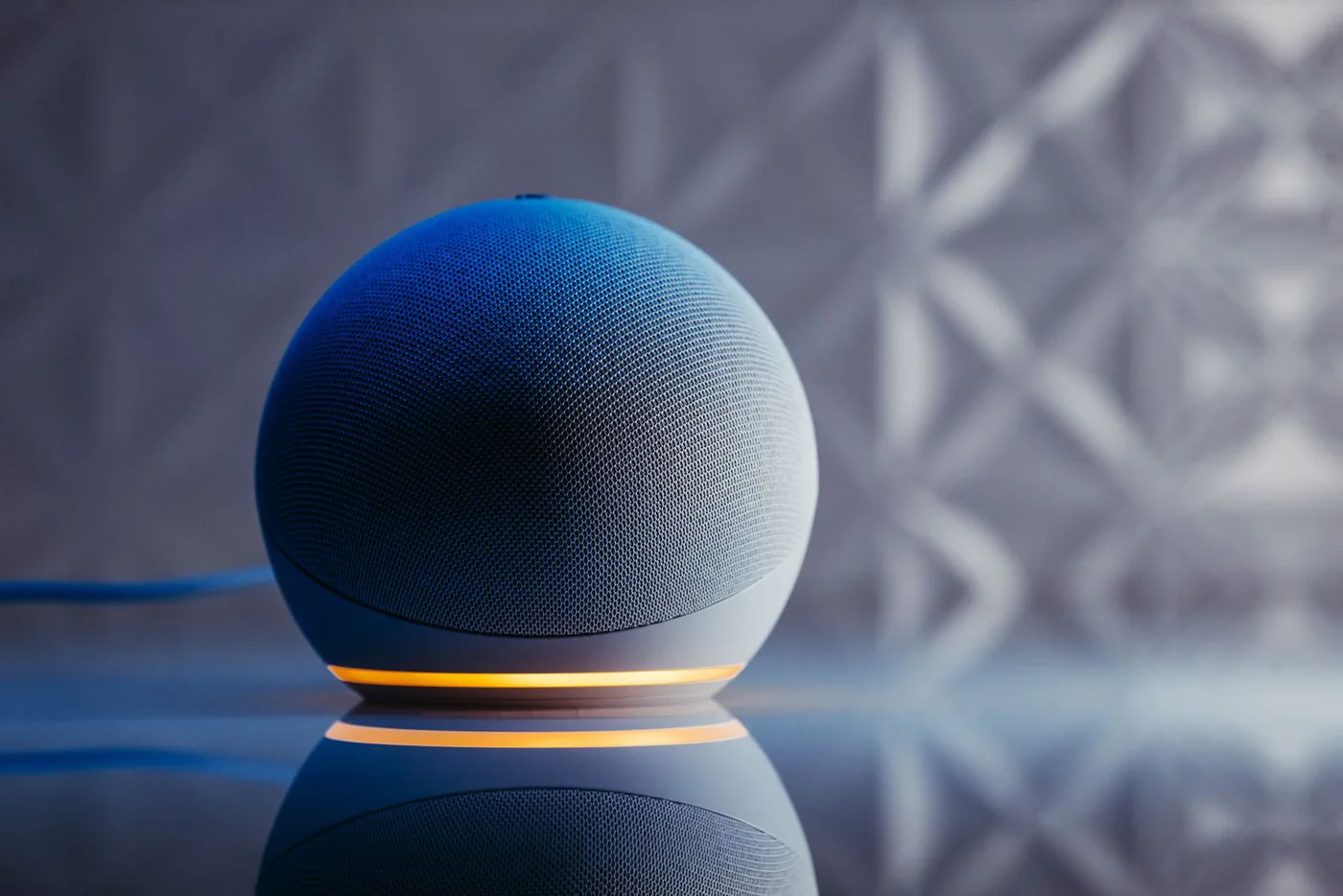 Spherical blue smart speaker with an illuminated base on a reflective surface