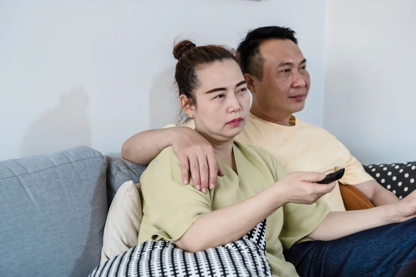 Couple sitting together on a couch with a television remote control
