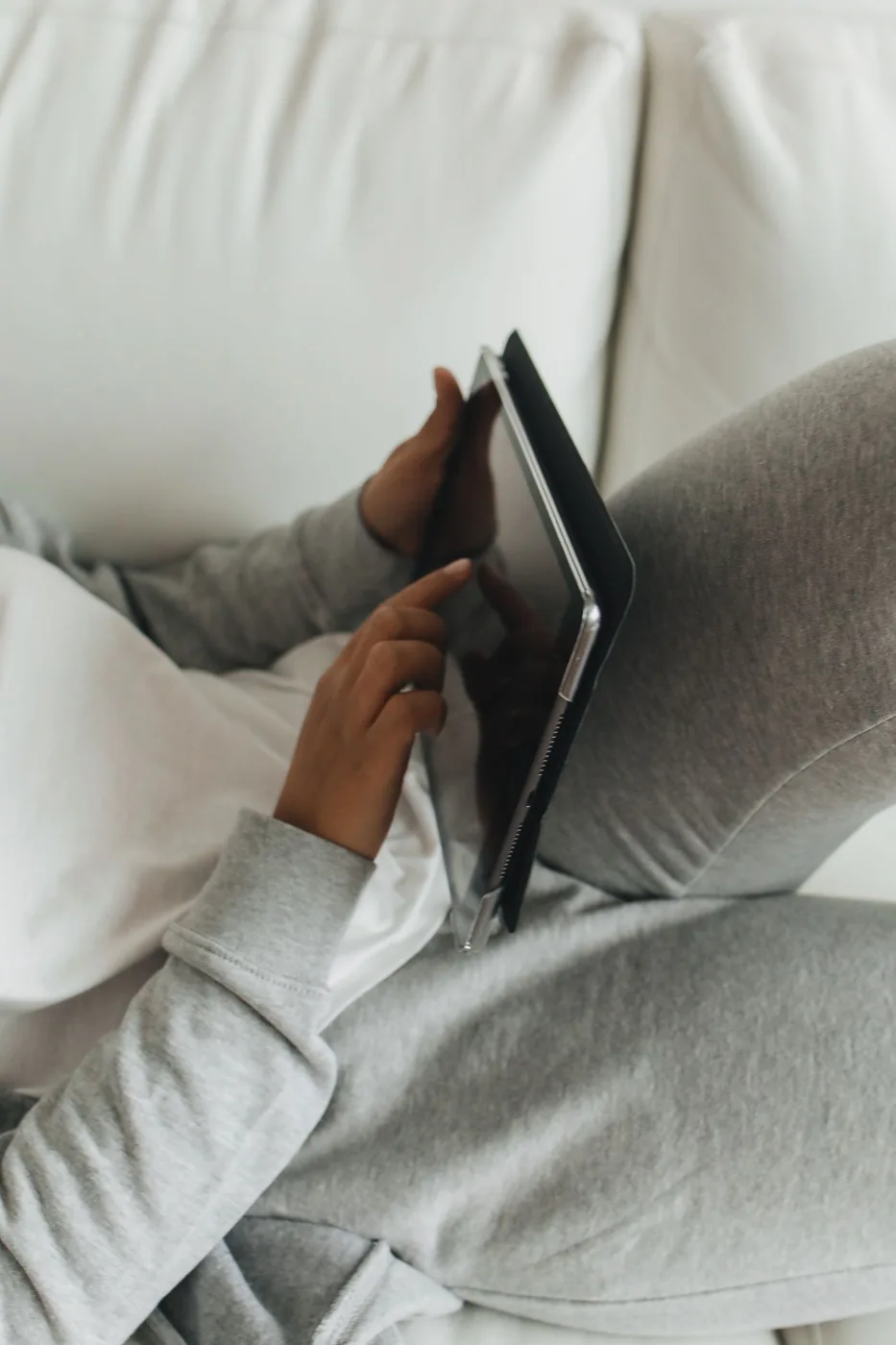 Woman using a tablet while sitting on a couch at home