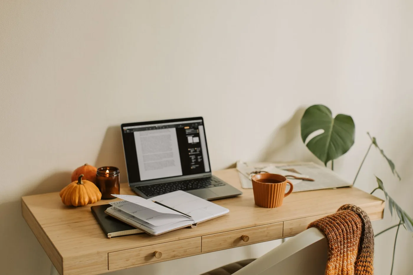 Laptop, calendar and a mug on a home office desk with autumn decorations
