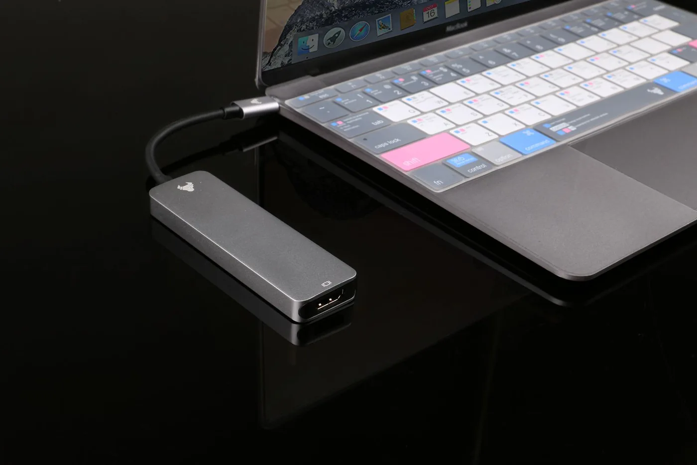 USB hub connected to a laptop on a reflective dark desk